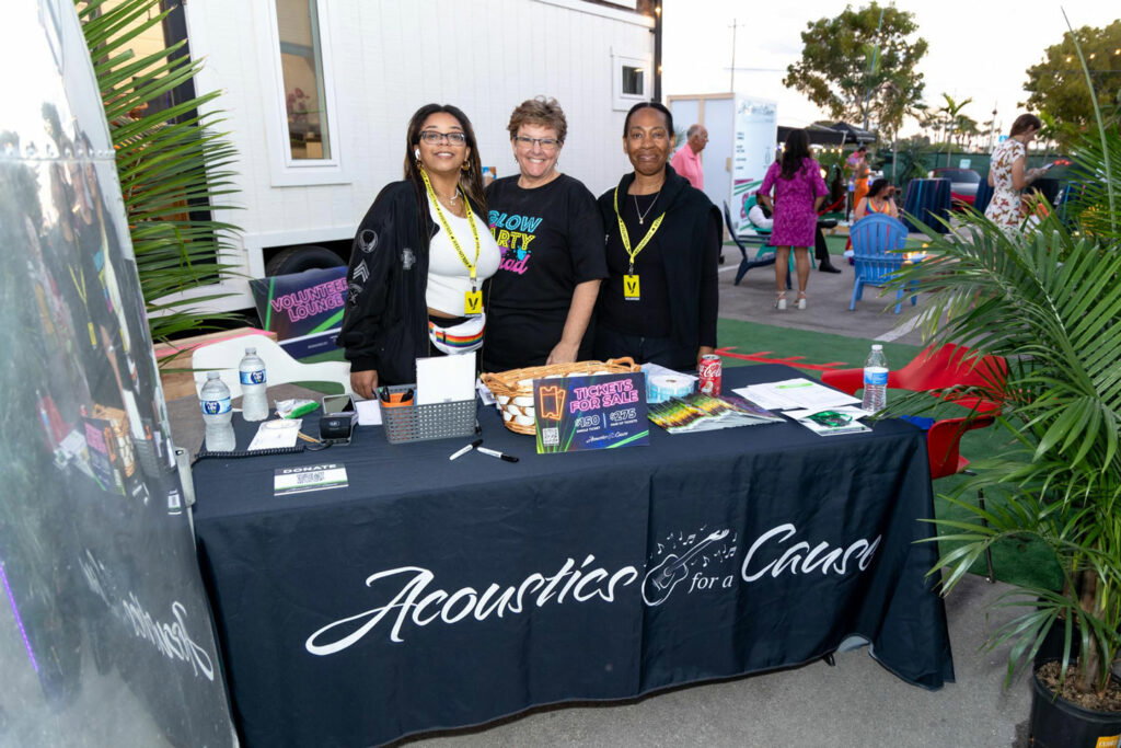 ticket table at entrance of charity event. with three women standing behind it, volunteering.